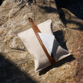Songmont tissue box cover in natural canvas with a brown leather strap and gold logo, shown on a rock.