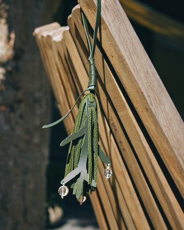 Forest green leather charm with leaf design and clear beads, inspired by Paris. A Songmont accessory.