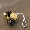 Yellow leather crab charm with textured brown body and white strap on sand