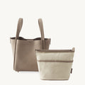 Medium Song Bag in taupe leather with a removable beige canvas inner pouch. Features adjustable strap and magnetic closure.