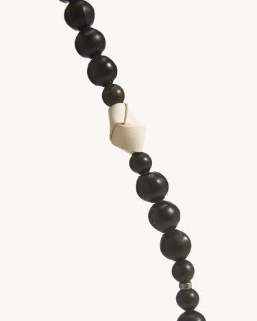 Small Carefree Thread Charm with alternating dark wooden and natural beads, featuring a white leather knot detail.