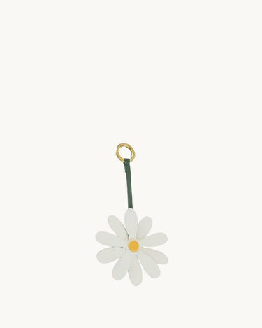 White leather daisy charm with yellow center on a green strap and gold ring.