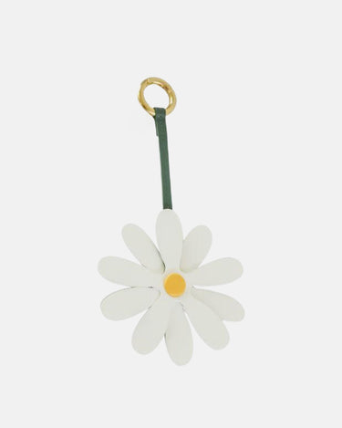 White leather daisy charm with yellow center and green strap on a gold ring