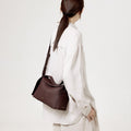 Burgundy leather Drippy Roof Bag worn by a woman, showcasing its structured silhouette and pebbled texture.