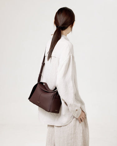 Burgundy leather Drippy Roof Bag worn by a woman, showcasing its structured silhouette and pebbled texture.