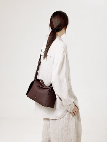 Burgundy leather Drippy Roof Bag worn by a woman, showcasing its structured silhouette and pebbled texture.