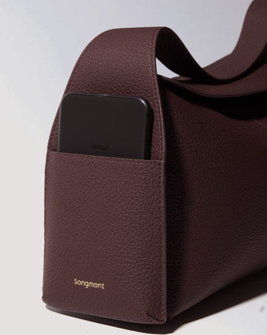 Burgundy leather Drippy Roof Bag with iPhone in exterior pocket and gold Songmont logo.