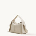 Light beige full-grain leather Drippy Roof Bag with textured finish, flap closure, and adjustable strap.