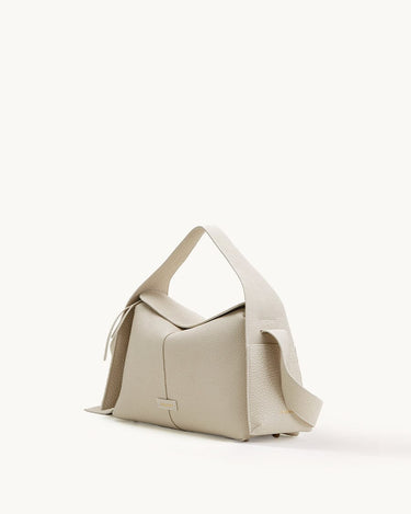 Light beige full-grain leather Drippy Roof Bag with textured finish, flap closure, and adjustable strap.