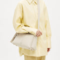 White full-grain leather Drippy Roof Bag with adjustable strap worn by a model in a yellow outfit.