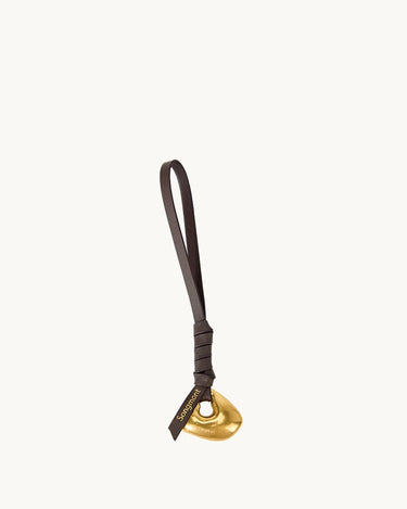 Faith Stone Charm accessory with golden abstract charm and dark leather strap, featuring 'Songmont' logo.