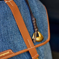 Faith Stone Charm bag in denim with tan leather trim, featuring a gold 'Songmont' logo charm and hardware.