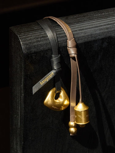 Faith Stone Charm & Prayer Wheel Charm Set in Sandal and Onyx colors, featuring gold-toned pendants.