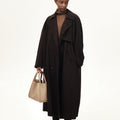 Large Song Bag in Cream Apricot, a textured leather tote carried by a woman in a dark brown trench coat.