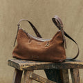 Large Yore Hobo Bag in sandal suede on wooden stool, featuring adjustable strap and 'songmont' logo.
