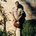 Woman in safari outfit holding a brown suede large Yore Hobo Bag with fringed detail.