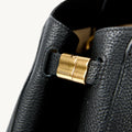 Black full-grain leather Yore tote bag detail with gold "Songmont" logo clasp.