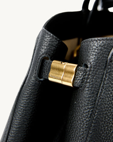 Black full-grain leather Yore tote bag detail with gold "Songmont" logo clasp.
