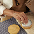Person applying Leather Care Balm with a cloth from a bamboo container. Includes "songmont" logo.