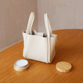 Cream leather handbag with beeswax care balm on a wooden table, perfect for leather care.