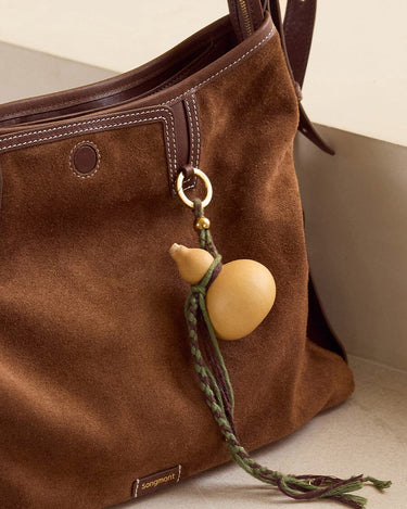 Brown suede Songmont bag with lucky gourd charm and braided cords.