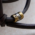 Lucky Pouch Charm: Leather strap with gold and silver beads, featuring etched designs.