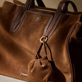 Brown suede duffel bag with leather trim and a small pouch, featuring the Songmon logo.
