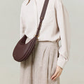 Burgundy Luna Bag crafted from textured leather with adjustable strap, worn by a model.