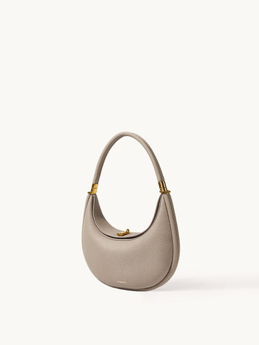 Textured pebble leather Luna Bag in Cobble with gold hardware and a curved top handle.