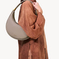 Luna Bag in Cobble, a textured full-grain leather crossbody bag worn by a woman.