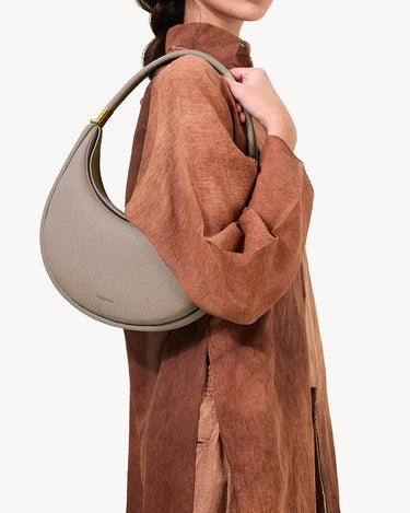 Luna Bag in Cobble, a textured full-grain leather crossbody bag worn by a woman.