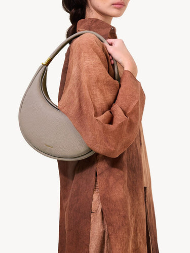 Luna Bag in Cobble, a textured full-grain leather crossbody bag worn by a woman.