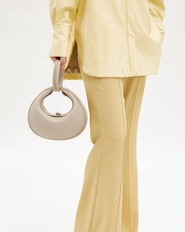 Ivory Luna Bag with crescent shape and top handle, made of full-grain leather.
