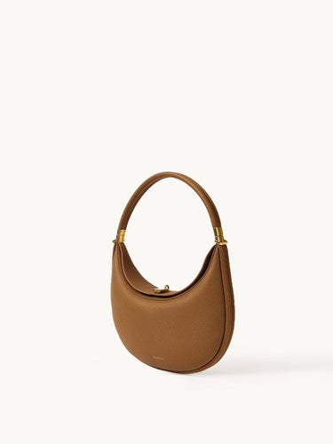 Luna Bag: A brown full-grain leather shoulder bag with gold hardware and a curved silhouette.