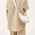 Luna Bag in Eco Cloud vegan leather worn crossbody by a person in a beige linen outfit.
