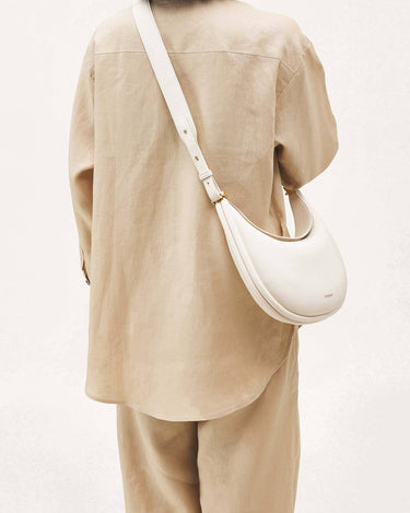 Luna Bag in Eco Cloud vegan leather worn crossbody by a person in a beige linen outfit.