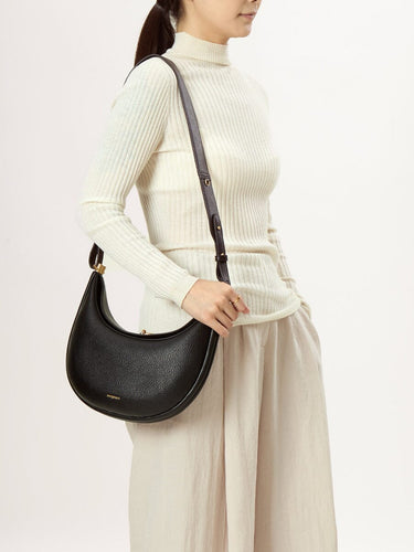 Luna Bag in Eco Onyx vegan leather with gold clasp and dark strap, worn by a model.