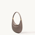Luna Bag in taupe full-grain leather with gold-tone hardware and adjustable strap.