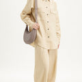 Luna Bag in grey full-grain leather with adjustable strap, worn with a tan linen outfit.