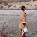 A woman in a tan outfit holds a white Medium Gather Bag Set with a beaded charm.