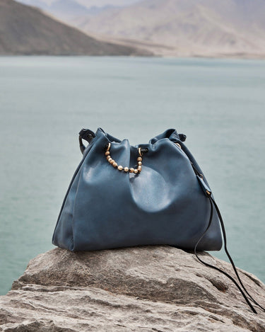 Blue Nappa leather Medium Gather Bag Set with beaded drawstring on rock by water