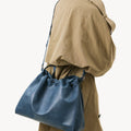 Medium Gather Bag Set in navy blue leather, worn by a person in a tan trench coat.