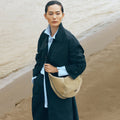 Large Luna Hobo Bag in Dune Suede on a woman by the ocean