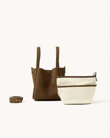 Medium Song Bag in Agarwood nubuck leather with a cream canvas inner pouch and adjustable strap.