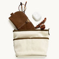 Medium Song Bag in cream canvas with brown leather accents, featuring glasses, AirPods case, and claw clip.