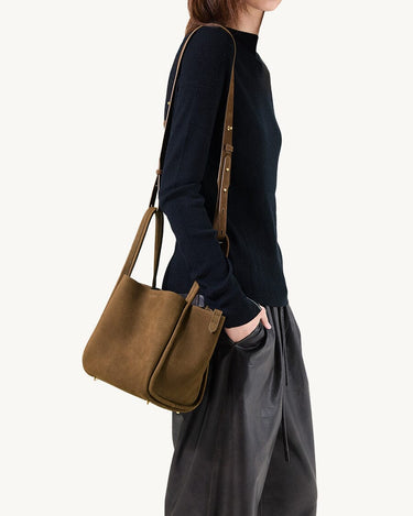 Medium Song Bag in Agarwood nubuck leather with adjustable strap, worn crossbody by a model.