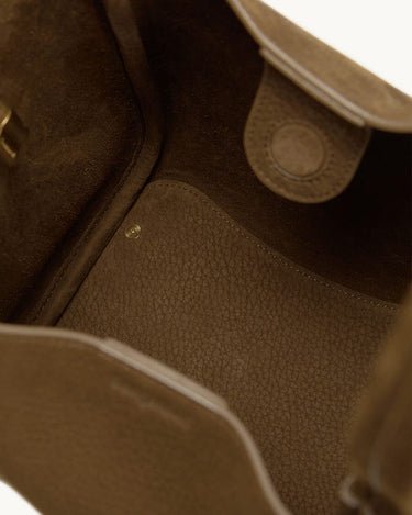 Inside view of the Medium Song Bag in Agarwood, showing the textured leather interior and a magnetic closure tab.