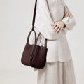 Medium Song Bag in burgundy pebbled leather with adjustable strap, worn crossbody by a woman.
