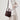 Medium Song Bag in burgundy pebbled leather with adjustable strap, worn crossbody by a woman.