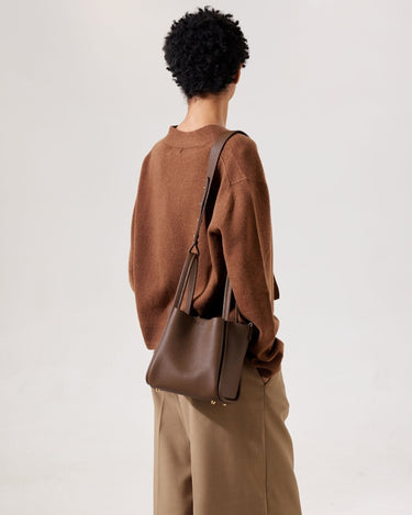 Medium Song Bag in chocolate pebbled leather with gold hardware, worn on shoulder by a person in brown sweater.